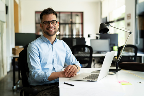 Young businessman sitting with a laptop open in an office